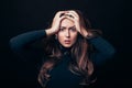 Upset offended beautiful woman holding her hands on head isolated on black background