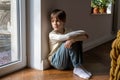 Upset offended child sit on floor look to window think about family problems, failures with peers