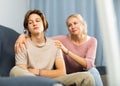 Upset and offended teenager sitting on sofa while mother soothing him Royalty Free Stock Photo