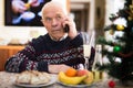 Upset older man talking on phone at table during New Year celebration