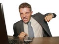 Upset and overwhelmed businessman in suit and tie working at office desk punching laptop computer suffering stress in financial Royalty Free Stock Photo