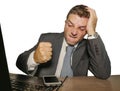 Upset and overwhelmed businessman in suit and tie working at office laptop computer desk punching mobile phone suffering stress in Royalty Free Stock Photo