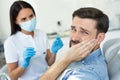 Upset patient touching face while having toothache near dentist