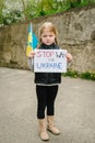 Upset poor toddler girl kid protesting war conflict raises banner with inscription message text Stop war in Ukraine and blue-