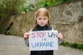 Upset poor toddler girl kid protesting war conflict raises banner with inscription message text Stop war in Ukraine. Crisis, peace