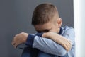 Upset preteen boy sitting at grey wall Royalty Free Stock Photo