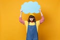 Upset puzzled girl teenager in french beret, denim sundress hold blue empty blank Say cloud, speech bubble isolated on Royalty Free Stock Photo