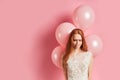 Upset redhaired girl in white wedding dress with air balloons
