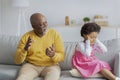 Upset sad black little girl closes her ears and does not want to listen to elderly man