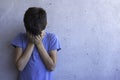 Upset sad boy stand alone and leaning on gray wall. Learning difficulties, family problems, bullying, depression, stress