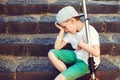 Upset sad kid sitting on the stairs outdoors. Tired boy after riding on scooter Royalty Free Stock Photo