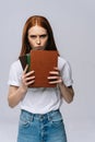 Upset sad young woman college student holding book and looking at camera on isolated background. Royalty Free Stock Photo