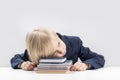 Upset schoolboy with pile of school books and notebooks. Tired or bored boy sleeps at the table Royalty Free Stock Photo