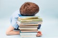 Upset schoolboy sitting with pile of school books. boy sleeping on a stack of textbooks Royalty Free Stock Photo