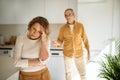Upset senior woman crying in kitchen while arguing with husband, angry man standing on background and blaming wife Royalty Free Stock Photo