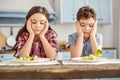 Upset siblings looking sadly at the vegetables