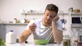 Upset single man eating tasteless cereals for breakfast, lack of appetite Royalty Free Stock Photo