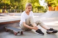 Upset skater girl holding her painful leg with skateboard near while spending time at skatepark Royalty Free Stock Photo