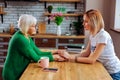 Upset sorrowful pensioner expressing emotions while talking to young lady