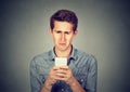 Upset stressed man holding cellphone disgusted with message received Royalty Free Stock Photo