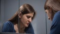 Upset stressed woman sighs at bathroom and looks in her reflection in mirror. Concept of depression, stress, mental illness and Royalty Free Stock Photo