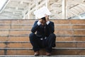 Upset stressed young Asian business man sitting on stairs and suffering from severe depression. Unemployment and layoff concept