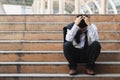 Upset stressed young Asian business man in suit with hands on head sitting on stairs. Unemployment and layoff concept Royalty Free Stock Photo