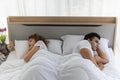 Upset stressed young couple in bed lying backs to each other. Relationship and problems couples concept Royalty Free Stock Photo