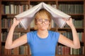 Upset student in library holding open book over her head