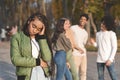 Upset Teen Black Girl With Friends Gossiping In Background