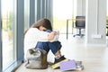 Upset teen girl sit on floor sadly look out window worried about teenage problem at school and communication with parent