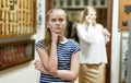 Upset teen girl standing in museum of art, mother on background Royalty Free Stock Photo