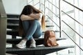 Upset teenage girl with backpack sitting on stairs