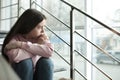 Upset teenage girl sitting on stairs indoors. Royalty Free Stock Photo