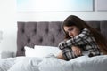 Upset teenage girl with smartphone sitting on bed Royalty Free Stock Photo