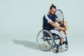 Upset tennis player sitting in wheelchair and holding tennis racquet and ball Royalty Free Stock Photo