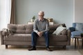 Sad thoughtful retired man sits on couch at home alone Royalty Free Stock Photo