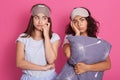 Upset and tired women standing against pink studio wall with exhausted facial expressions after having fun together, posing in