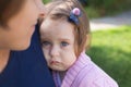 Upset toddler girl with blue eyes embraced by her mother, wearing blue t-shirt Royalty Free Stock Photo