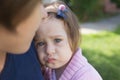 Upset toddler girl with blue eyes embraced by her mother, wearing blue t-shirt Royalty Free Stock Photo