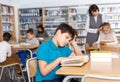 Upset tween boy reading in school library Royalty Free Stock Photo