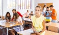 Upset tween girl sitting on table in schoolroom during recess