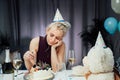 Upset, unhappy attractive woman eating festive cake while celebrating birthday at home, sitting alone at served table