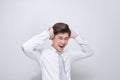 Upset unhappy young man in white t-shirt squeezing head with hands, suffering from headache. People, stress, tension and migraine Royalty Free Stock Photo