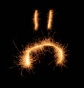 Upset weird sad smiley drawn with sparkles on black background Royalty Free Stock Photo
