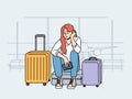 Upset woman airport passenger sits near luggage and waits for plane that is late due to bad weather Royalty Free Stock Photo