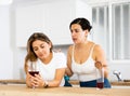 Upset woman drinking wine in kitchen while girlfriend consoling her Royalty Free Stock Photo