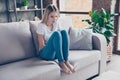 Upset woman has first symptoms of pms. She is sitting on a sofa