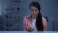 Upset woman holding pills in palm behind rainy window, expensive medicine