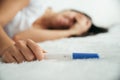 Upset woman lie sad in the bed with negative pregnancy test